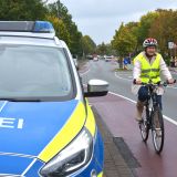 Eine Fahrradfahrerin fährt auf dem Radstreifen neben einem Streifenwagen der Polizei Bielefeld.