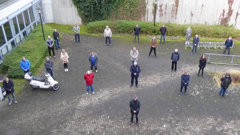 Mehrere Personen stehen zur Schweigeminute im Innenhof der Liegenschaft in der Lerchenstraße.