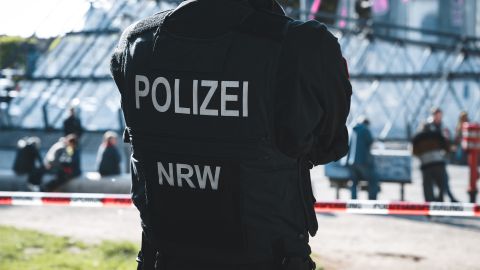Ein Polizist steht vor einer Absperrung.