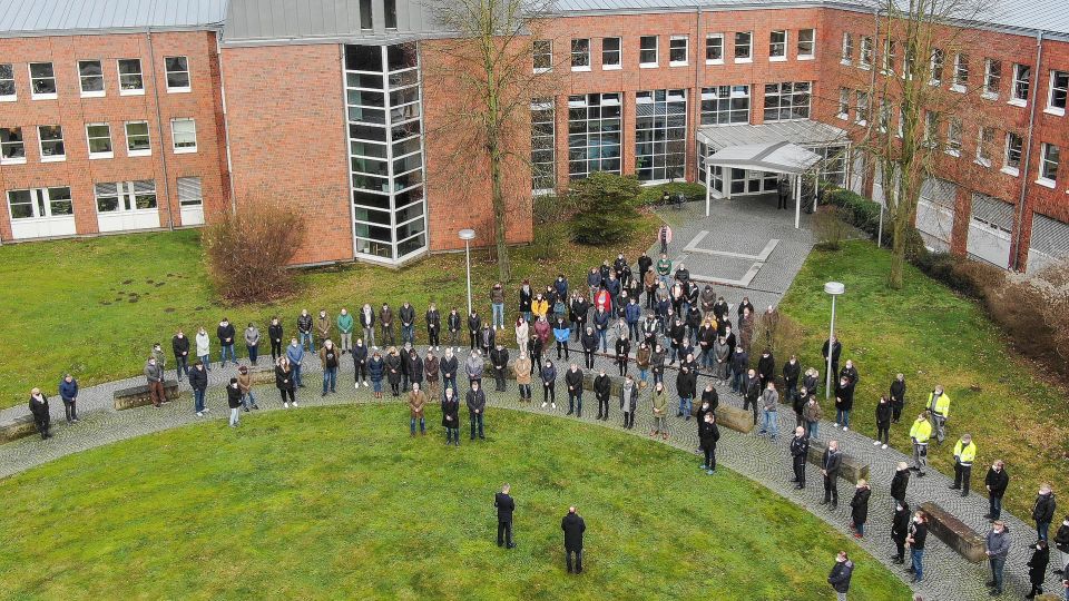 Viele Personen stehen zur Schweigeminute vor dem Bielefelder Polizeipräsidium.
