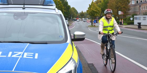 Eine Fahrradfahrerin fährt auf dem Radstreifen neben einem Streifenwagen der Polizei Bielefeld.
